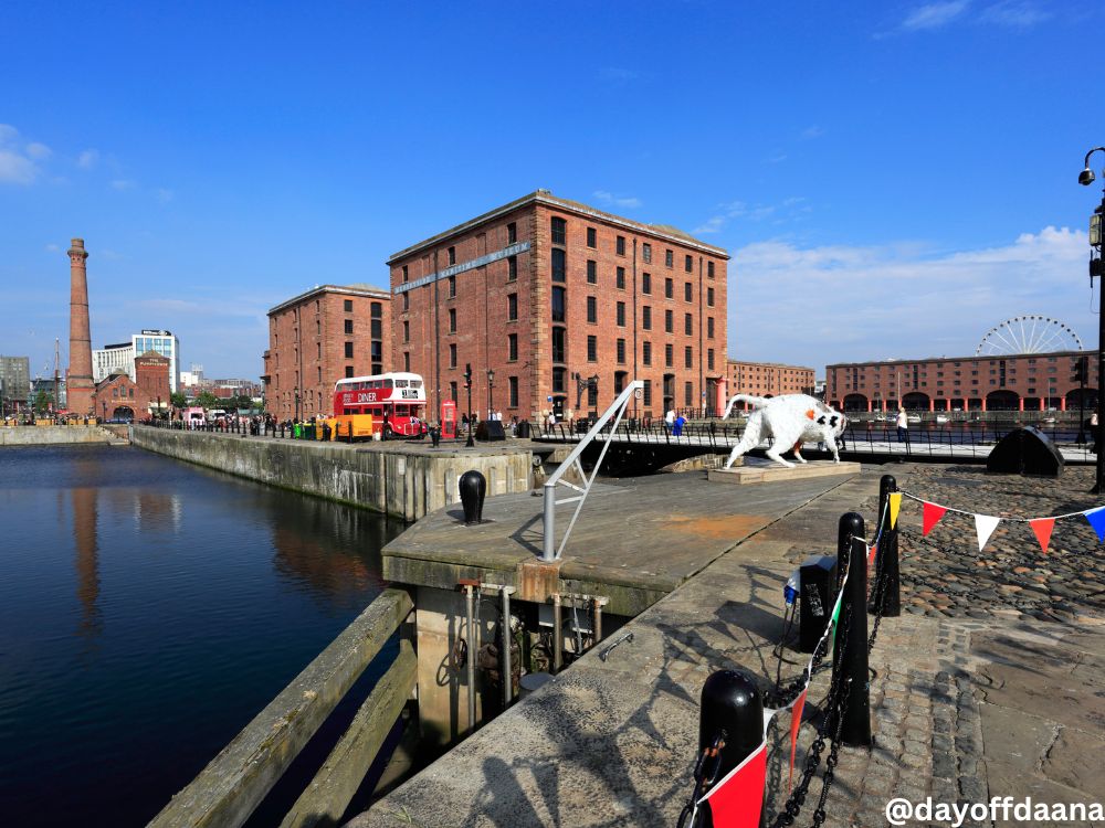 Albert Dock em Liverpool, região turística com comércio, museus e prédios históricos de tijolos vermelhos, com roda-gigante ao fundo