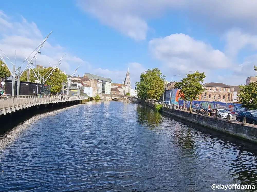 <cidade de cork, rio lee, a esquerda sento da cidade, e a direita mural love Cork, igreja no fundo>