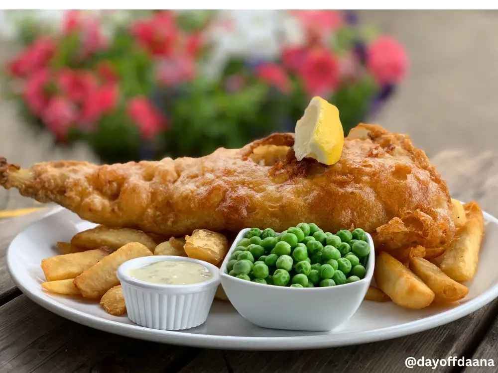 Alt= Fish and Chips - prato tradicional para comer na irlanda com peixe frito, batatas fritas, acompanhado de molgo tartaro e ervilhas frescas