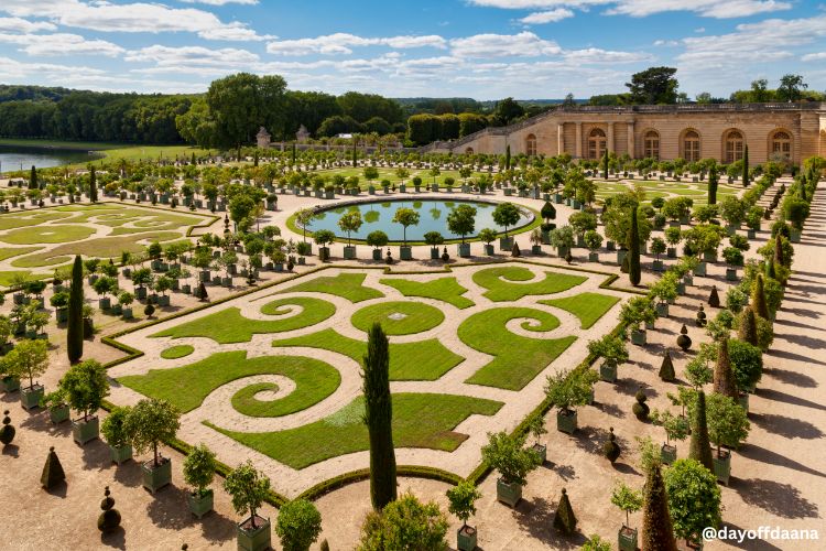 Alt: Foto do imponente e famoso Jardim de Versalhes, com desenhos geométricos entre as plantas, estruturas e fontes, um passeio incrivel de bate e volta por Paris.