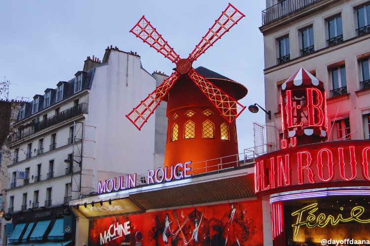 Alt: Foto do Moulin Rouge e seu famoso moinho acima. O local, conhecido pelas danças de can-can, vale a pena para assistir a um show.