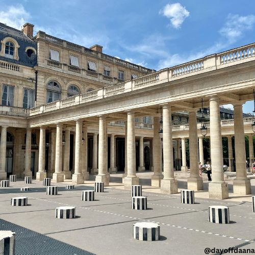 Alt: Pátio do Palais Royal com colunas listradas, uma opção instagramável.