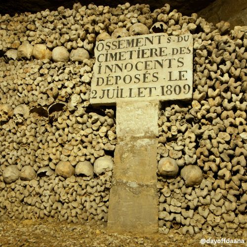 Alt: Catacumbas de Paris – Foto mostrando ossos de várias pessoas no local, uma atração histórica e curiosa da cidade.