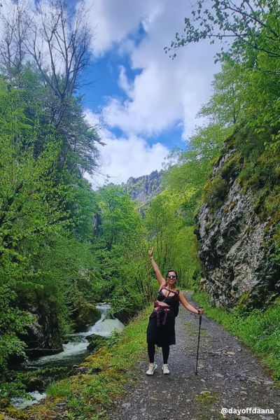 Eu estou no meio da trilha, cercada de pedras e muita vegetação, aproveitando a experiência de viajar sozinha