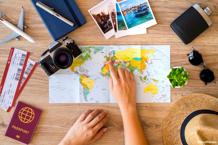 mapa mundi no centro, mulher apontando paises da europa como escolha de destino e fazendo planos de viahem sozinha, ao lado algumas coisas como passaporte, bilhetes, , maquina fotografia, oculos de sol