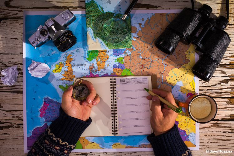 Pessoas escrevendo na agenda dias de viagem com mapa da mao, binoculos e maquina fotografica.