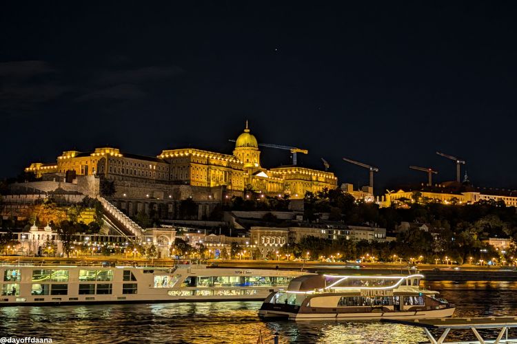 o_que_fazer_em_Budapeste_Castelo_Buda "Mostrando o Castelo de Buda iluminado e o rio Danúbio com embarcações à frente. Um passeio pelo Danúbio é um ótimo exemplo do que fazer em Budapeste
