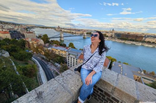 Estou no meio da foto, dando risada. Atrás de mim, você vê o rio Danúbio e o Parlamento. Estou no complexo do Castelo de Buda, uma ótima opção do que fazer em Budapeste.
