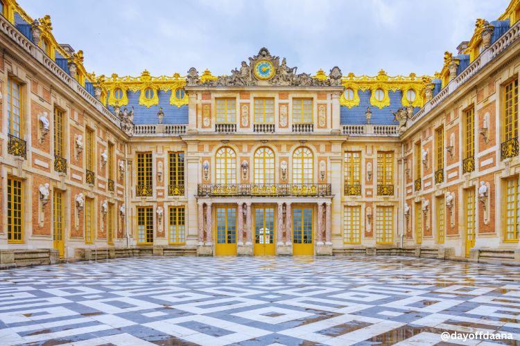 entrada_Palacio de_versalhes Alt = Entrada principal do Palácio de Versalhes, mostrando as alas leste e oeste, com detalhes ornamentais dourados no topo.